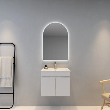 Bathroom vanity with illuminated arch mirror on a gray wall.